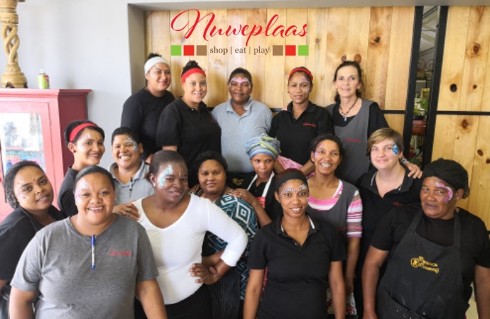 The Nuweplaas team gathered under the shop sign